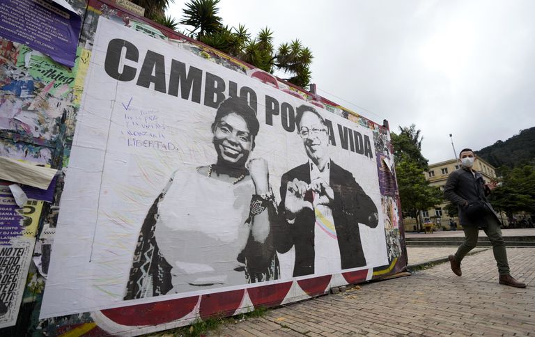 Um homem passa por um cartaz de campanha do candidato presidencial Gustavo Petro e sua companheira de chapa Francia Márquez, com a coalizão Alianza Histórico, em Bogotá, Colômbia, quarta-feira, 25 de maio de 2022.
