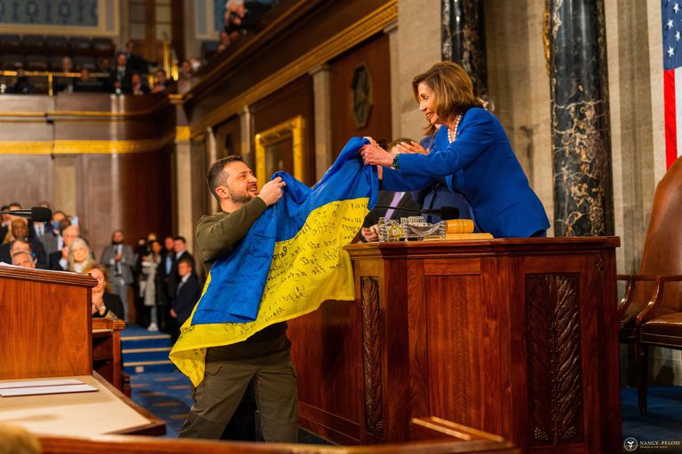 El presidente de Ucrania, Volodimir Zelenski, entrega a la presidenta de la Cámara de Representantes de Estados Unidos, Nancy Pelosi, una bandera de Ucrania